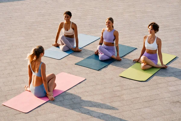 Women in sportswear doing yoga on rubber mats on the roof of a house overlooking the sea. Sport and recreation. Morning exercise outdoors. Active and healthy lifestyle.