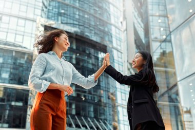 Farklı ırktan başarılı iş kadınlarından oluşan bir ekip ofis binalarının arka planına karşı beşlik çakıyor. Çeşitli kadınlar binaların arka planında cadde boyunca yürürler..