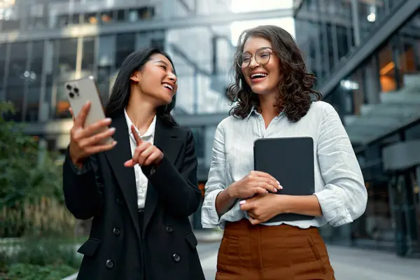 Çok ırklı başarılı iş kadınlarından oluşan bir ekip, ofise doğru yol alırken stratejiden, kahve içmekten ve telefon kullanmaktan bahsediyorlar. Arka planda binalar olan çeşitli kadınlar dışarıda yürüyor..