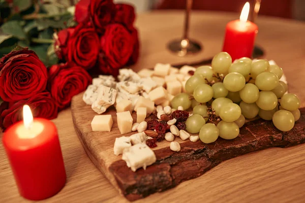 情人节快乐 左边的节日餐桌 浪漫的烛光晚餐 奶酪片 玫瑰束 礼物和桌上的酒杯 — 图库照片