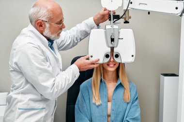 Bir kadın optik mağazada bir göz doktoruyla göz testi yapar, bir optometrist klinikte bir kadının görüşünü kontrol eder. Oftalmoloji ve görme düzeltmesi.