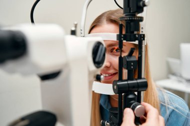 Göz muayenesi ya da bir kadının optometriste veya göz doktoruna vizyon muayenesi. Bir göz doktoru, hastanın görme yetisini göz doktoruyla test eder veya irinin ya da retinanın sağlığını kontrol eder..