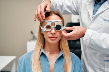Optik atölyesindeki kadın göz testi yapıyor. Optimetrist klinikteki kadın hasta için görüş testi yapıyor. Oftalmoloji ve göz düzeltmesi.