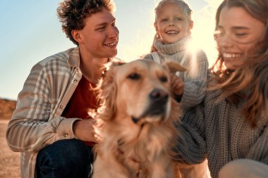 Küçük tatlı bir kızı olan genç bir çift ve sevgili av köpekleri hafta sonları serin havalarda kumsalda yürüyüp dinleniyorlar. Aile evcil hayvanla seyahat ediyor.