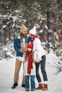 Mutlu Noeller ve mutlu yıllar. Çocuklu mutlu bir aile ve karlı havada ormanın arka planında oynayıp eğleniyorlar..
