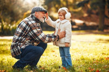 Büyükbaba sonbaharda parkta küçük tatlı torunuyla yürüyor ve oynuyor..