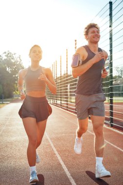 Stadyumda koşan bir çift spor giysisi. Sabah egzersizleri ve koşu. Spor ve Olimpiyat Oyunları, aktif yaşam tarzı.