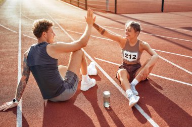 Stadyumda koştuktan ve beşlik çaktıktan sonra spor giyimli bir çift koşucu. Sabah egzersizleri ve koşu. Spor ve Olimpiyat Oyunları, aktif yaşam tarzı.