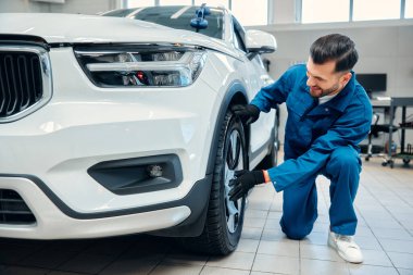 Araba temizliği. Adam mikrofiberi elinde tutuyor ve arabayı cilalıyor. Araba yıkamada araba lastiklerini yıkayan işçi mikrofiber bezle araba temizleyen adam, araba temizleme konsepti..