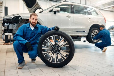 Tamirci garajda çalışıyor ve tekerlek alaşımı değiştiriyor. Tamir ya da bakım servisi. Tamirhanede lastik tutan tamirci. Kış ve yaz lastiklerinin yenisi..