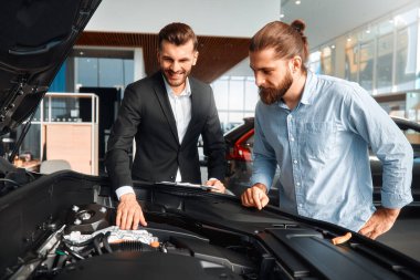 Satıcı veya araba satıcısı ve müşteri veya müşteri showroom yeni ve ikinci el araçların motor performansını sunan araba bayilik, erkek kaputun altında bakan