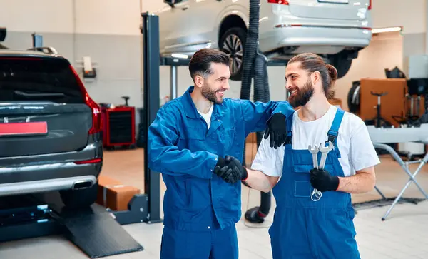 两个机械师正在修理车间里的一辆汽车 汽车机械师详细检查了汽车 汽车维修中心 汽车服务 保养概念 — 图库照片