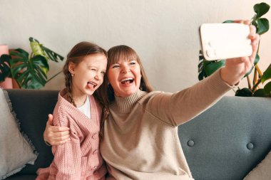 Torunumla büyükannem oturma odasındaki kanepede otururken akıllı telefondan selfie çekiyorlar. Anneler günü ve kadınlar günü konsepti.