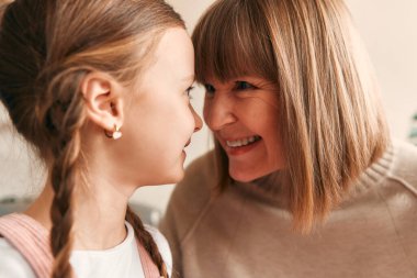 Sevimli bir torunu olan büyük anne, sıcak bir oturma odasında, kanepede oturup birlikte güzel vakit geçirirken sarılıyor..