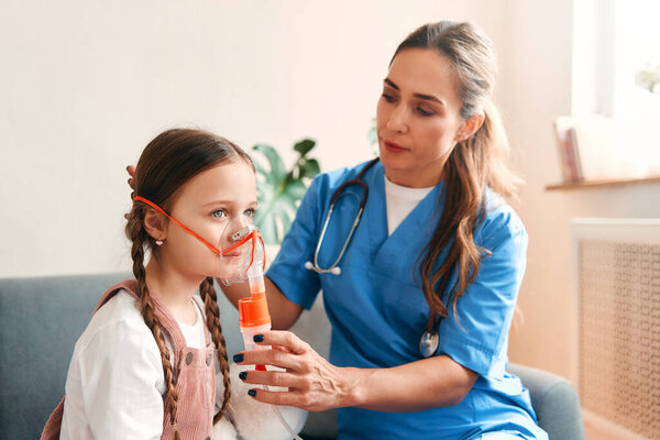 Женщина-педиатр надевает маску для вдыхания на ребенка дома. Обследование пациентов, здравоохранение и медицина.