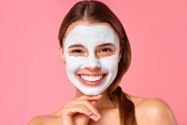 Güzel, mutlu bir kadın siyah noktalar ve pembe arka planda izole edilmiş büyümüş gözenekler için kilden yüz maskesi kullanıyor. Cilt bakımı, kozmetoloji, güzellik konsepti.