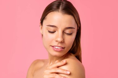 Neşeli genç bir kadın pembe bir arka planda parlak bir gülümseme sergiliyor, parlak cildini ve doğal güzelliğini sergiliyor. Sağlık, cilt bakımı ve pozitiflik için mükemmel..