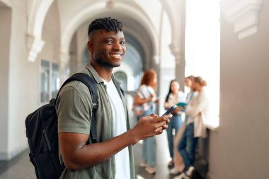 Üniversite koridorunda, sırt çantalı neşeli bir üniversite öğrencisi arkadaşlarıyla sosyalleşen bir akıllı telefon kullanıyor. Kampüsteki modern gençlik yaşam tarzını özetliyorlar.