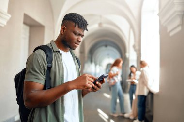 Üniversite koridorunda, sırt çantalı neşeli bir üniversite öğrencisi arkadaşlarıyla sosyalleşen bir akıllı telefon kullanıyor. Kampüsteki modern gençlik yaşam tarzını özetliyorlar.