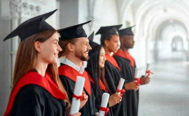 Bir grup farklı, neşe dolu mezunlar akademik başarılarını bir mezuniyet töreninde kutluyor, mutluluk ve memnuniyet saçan diplomalarını gururla gösteriyorlar.