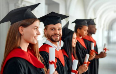 Bir grup farklı, neşe dolu mezunlar akademik başarılarını bir mezuniyet töreninde kutluyor, mutluluk ve memnuniyet saçan diplomalarını gururla gösteriyorlar.