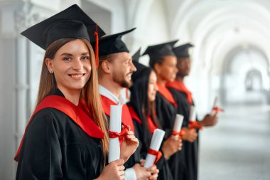 Bir grup farklı, neşe dolu mezunlar akademik başarılarını bir mezuniyet töreninde kutluyor, mutluluk ve memnuniyet saçan diplomalarını gururla gösteriyorlar.