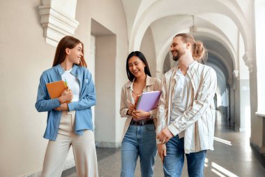 Onlar canlı bir okul koridorunda yürürken, çeşitli üniversite öğrencileri sınıfa giderken kitaplarını taşıyarak mutlu bir şekilde sohbet ediyorlar. Onlar arkadaşlığı, eğitimi ve akademik hedefleri somutlaştırıyorlar.