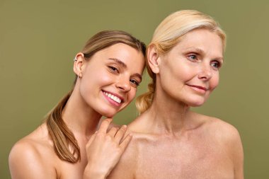 Zeytin arka planında duran parlak, sağlıklı cilde sahip genç ve olgun kadınlar. Kozmetoloji, cilt bakımı ve spa tedavileri. Estetik ameliyat ve yüz gerdirme.