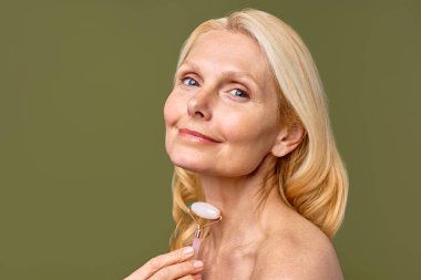 Işıl ışıl, gülümseyen bir kadın gül kuvars silindiri kullanırken cilt rutininin tadını çıkarıyor. Bu sadece doğal güzelliğini arttırmakla kalmıyor, aynı zamanda rahatlamasını ve iç huzurunu da arttırıyor.