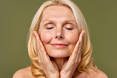 Güzel, olgun, orta yaşlı, parlak tenli, zeytinli bir kadın. Olgun yaşlı kadın yakın çekim. Sağlıklı yüz derisi, orta yaşlı cilt bakımı kozmetik ürünleri, kozmetoloji konsepti