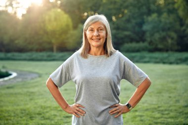 Neşeli, son sınıf öğrencisi bir kadın kollarını zarif bir şekilde açık havada, yemyeşil bir parkta uzatıyordu. Çevresinde yaşam, zindelik ve güzellikle dolu bir hayat sürüyordu.