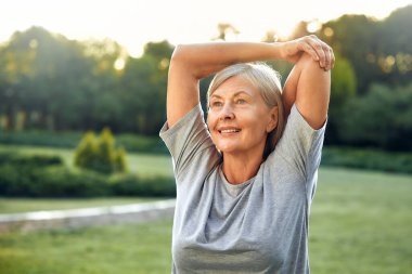 Neşeli, son sınıf öğrencisi bir kadın kollarını zarif bir şekilde açık havada, yemyeşil bir parkta uzatıyordu. Çevresinde yaşam, zindelik ve güzellikle dolu bir hayat sürüyordu.
