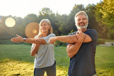 Neşeli bir çift, güneş batarken, dışarıda, sakin bir parkta birlikte uzanıyor. Zindelik ve refahı desteklerken, aynı zamanda, doğanın canlı yeşilliği içinde, birbirlerine eşlik ediyorlar. Güzellik.