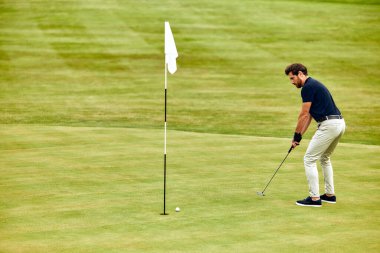 Yetenekli bir golfçü özenle zorlu yoldan önemli bir atış yapmaya hazırlanıyor. Bu atış, kursun canlı ve güzel manikürlü yeşili arasında hem yeteneğini hem de lazer gibi odaklandığını gösteriyor.