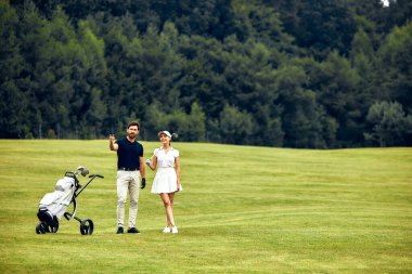Bir çift el ele yürür hayret verici bir resim yeşil alanda, bir bebek puseti yedekte, güzel vurgulayarak aile anlarının neşe ve sıcaklığını hafifçe doğada harcayan