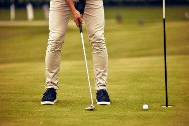 Kendini adamış bir golfçü güzel manikürlü bir yeşile vurmaya özen göstererek golfte önemli olan yoğun odaklanma ve dikkat çekici hassasiyeti gözler önüne seriyor.