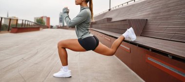 Genç bir kadın etkileyici fitness rutinini açık havada bir dizi hamleler yaparak sergiliyor, gücünü ve çevikliğini vurgulayarak nefes kesici ve resimsel manzaranın tadını çıkarıyor.