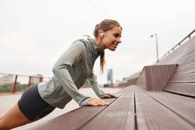 Formda bir kadın açık havada zorlu bir şınav egzersizi yapar etkileyici gücünü ve genel fitness seviyesini etkili bir şekilde gösterir. Bu sahne uygun ortam içeriği için idealdir