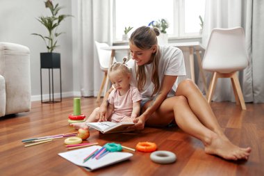 Sevgi dolu bir anne ve onun neşeli çocuğu arasında, yaratıcılıklarını ve hayal güçlerini ateşleyen renkli oyuncaklarla çevrili, sıcak ahşap bir zeminde, neşeli bir an paylaşılır.