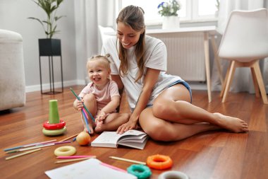 Sevgi dolu bir anne ve onun neşeli çocuğu arasında, yaratıcılıklarını ve hayal güçlerini ateşleyen renkli oyuncaklarla çevrili, sıcak ahşap bir zeminde, neşeli bir an paylaşılır.