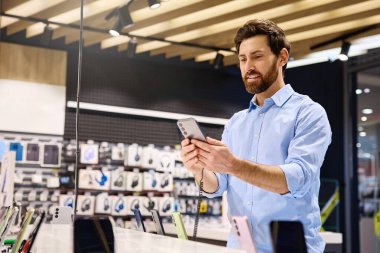 Mobil aksesuarlarla dolu hareketli bir perakende mağazasında, bir adam kendini akıllı telefonların çeşitli özelliklerini keşfetmeye kaptırırken, bir yandan da modern teknoloji aletleri ve vitrinlerle çevrili...