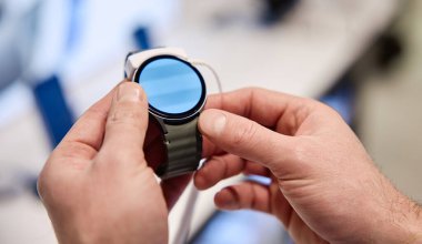 Yakın plan bir görüntüde, modern teknoloji ve şık tasarımın en son halini vurgulayarak, canlı ve ilgi çekici bir görüntüye sahip güzel tasarlanmış bir akıllı saati yakından inceleyen bir birey yer alıyor.