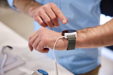 Bir adam, bir teknoloji mağazasında şık bir ukalalık tasarımı ve giyilebilir teknolojik ürünlerin gelişmiş işlevselliğini vurgulayarak şık bir zeka oyunuyla aktif olarak meşgul oluyor.