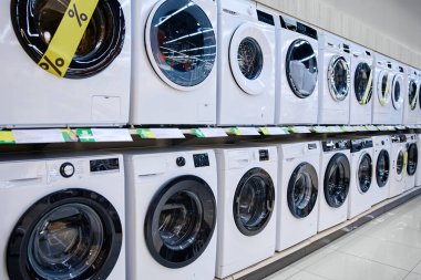 Şık, şık, modern çamaşır makineleri bir perakende mağazasında güzelce sergileniyor, cazip promosyon fiyatlarının yanı sıra çeşitli eşsiz tasarımlar sergiliyor.