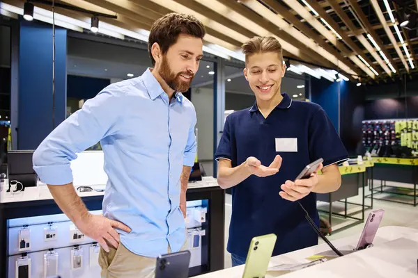 Modern bir perakende satış ortamında, müşteri en son akıllı telefonlar hakkında bilgili bir satıcıya hevesle konuşur ve etkileşim sırasında kişiselleştirilmiş servisin değerini vurgular.