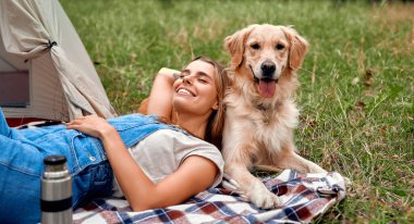 Neşeli bir kadın, açık havada derin bir barış kampı keşfediyor, neşeli golden retriever 'ıyla eğleniyor, ve doğanın nefes kesici güzelliği arasında paylaştıkları özel bağı kutluyor.