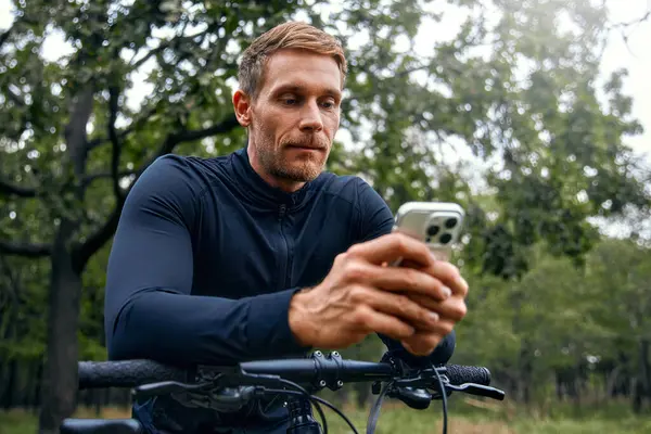 Bir bisikletçi akıllı telefonunu kontrol etmek için kısa bir süre ara verir. Bu arada doğanın dingin güzelliğinin tadını çıkarır. Modern teknoloji ve zindeliğin eşsiz karışımını mükemmel bir şekilde somutlaştırır.