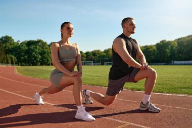 Atletik erkek ve kadın stadyum pistinde hamlesini yapıyor. Sabah egzersizi, esneme hareketleri ve sağlıklı yaşam tarzı konsepti..