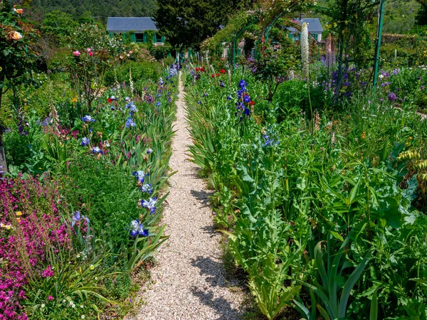 gravel path between flourishing plants at the former garden of the artist Claude Monet in the village of Giverny, France