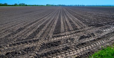 Avusturya 'nın bahar güneşinde Tullnerfeld bölgesinde karanlık toprak ve ağır traktör tekerlek izlerinin uzadığı boş bir alan.